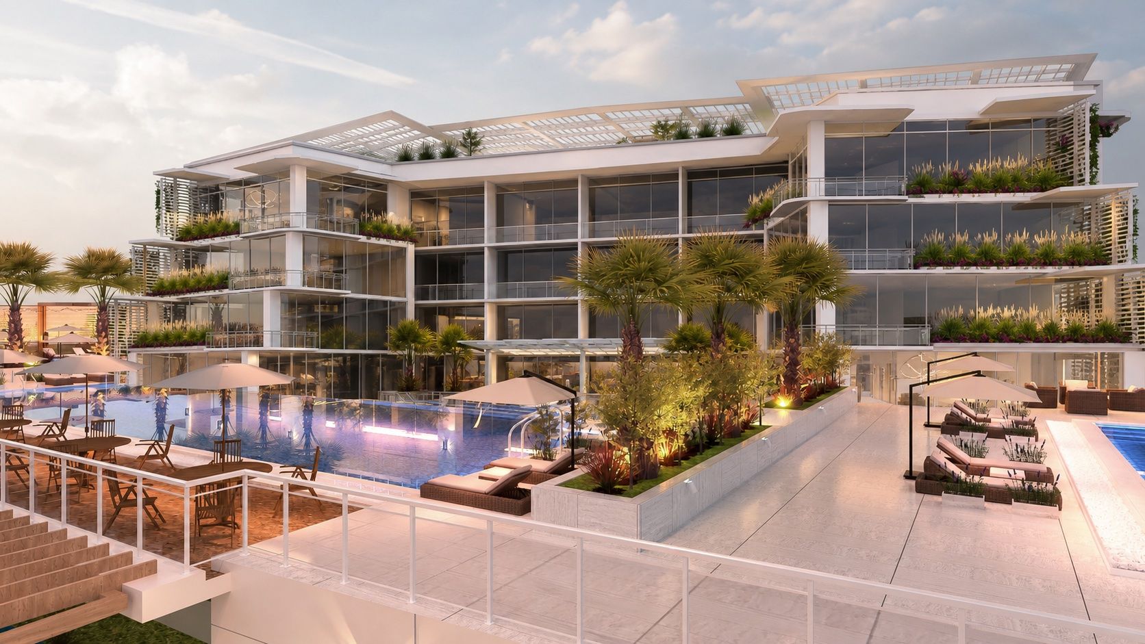 Pool deck at dusk — palms, cabanas and dining terraces beside the glass facade